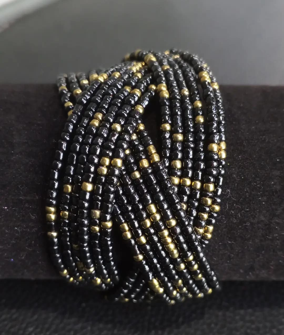 Beaded cuff wrap bracelet in black beads with gold accents.
