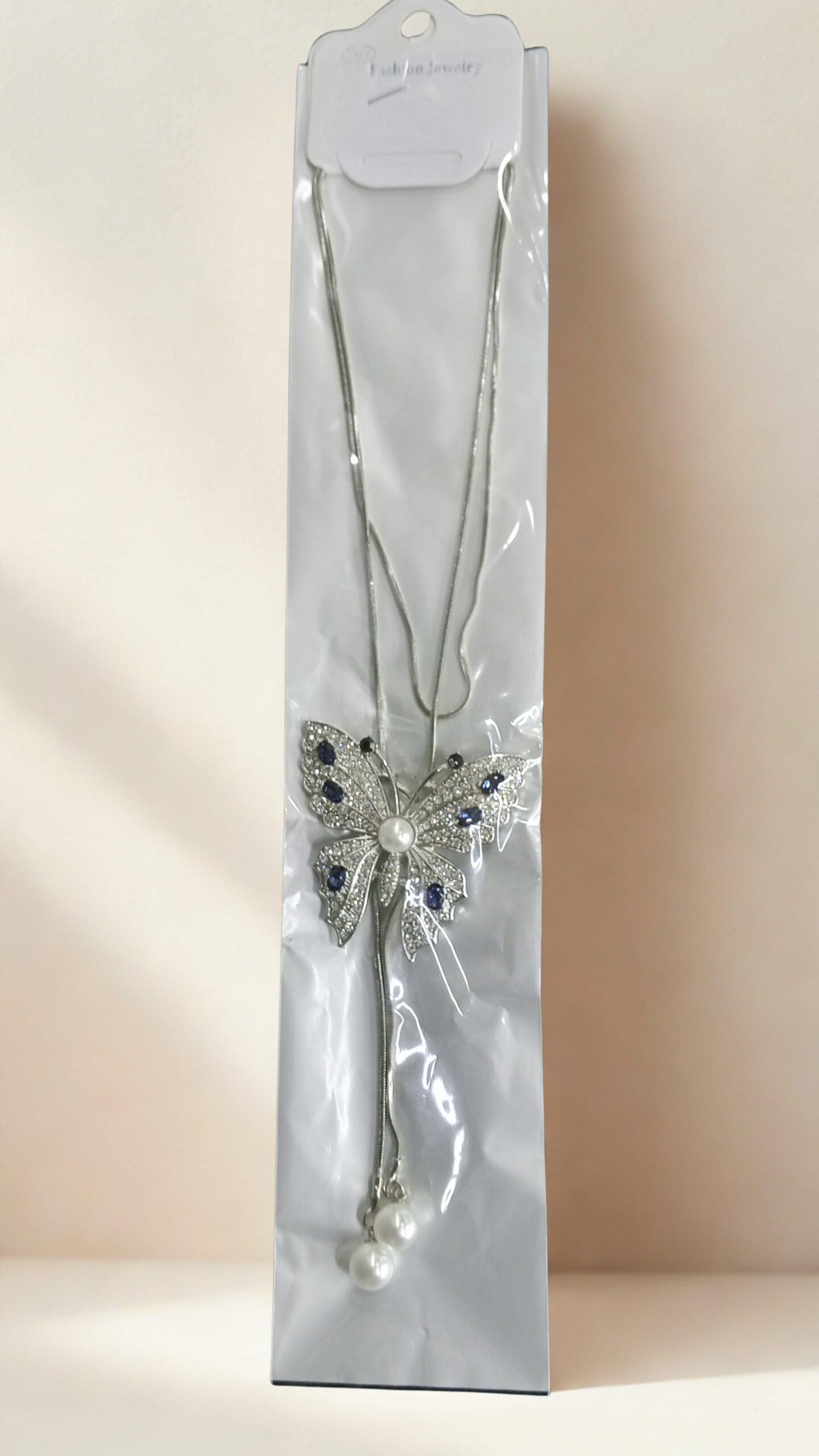 Silver long chain necklace with butterfly pendant featuring dark blue stones and pearl accents.