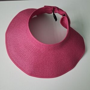 Pink woven straw sun visor hat with wide brim and black clasp strap.