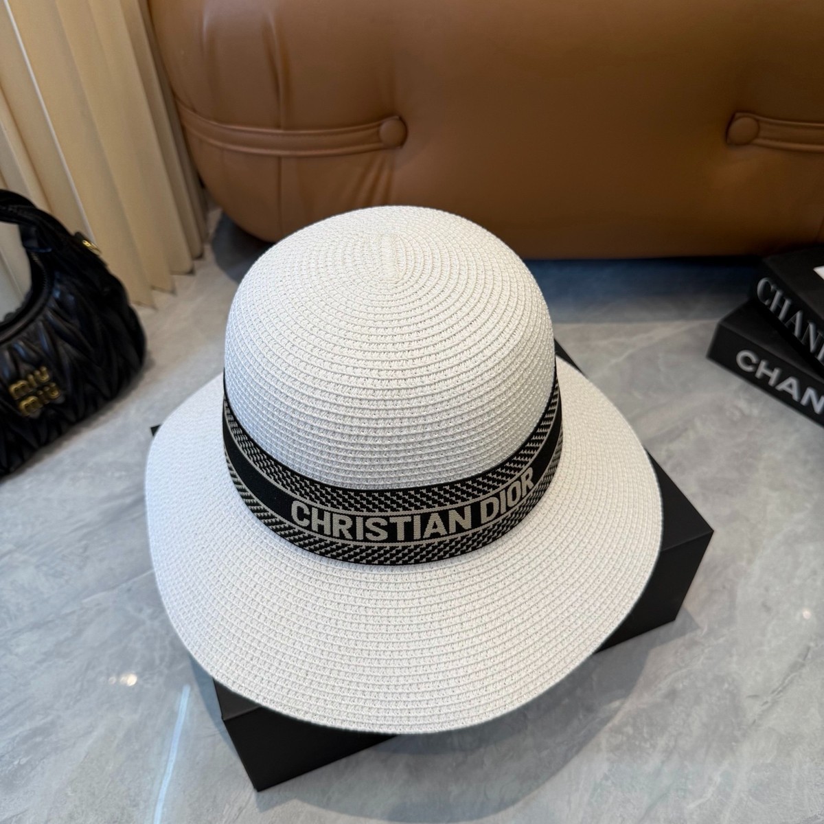 White woven fedora hat with wide brim and black band featuring Christian Dior logo.