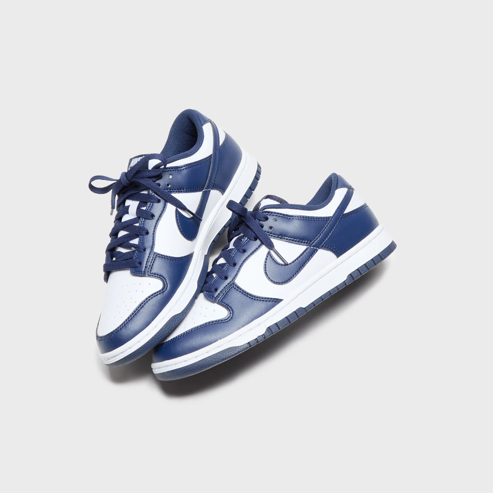 Nike Dunk Low Retro White Base with Navy Blue Overlays Sneakers Nairobi Kenya Nike Dunk Low Retro sneakers with white base, navy overlays, white swoosh, navy laces, and navy outsole Nairobi Kenya.