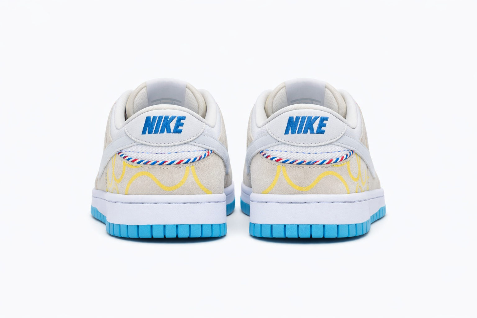 Nike Dunk Low SE Barber Shop Grey Sneakers Heel Branding Nairobi Kenya Nike Dunk Low SE Barber Shop Grey sneakers back view with beige and white upper, bold blue NIKE embroidery on heel tab, yellow wavy heel patterns, and striped trim Nairobi Kenya.