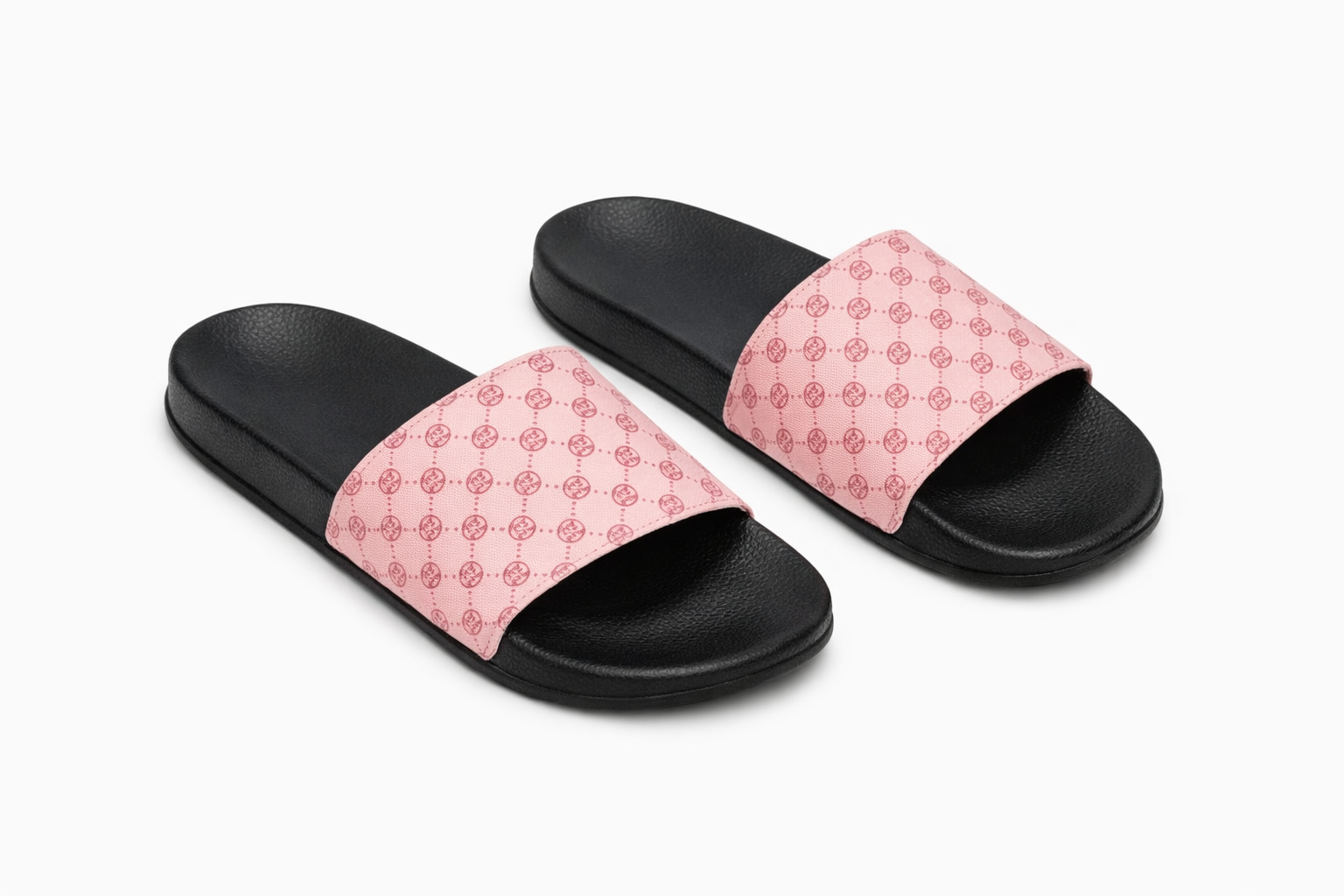 Black sole slide sandals with wide pink strap featuring repeating circular logo pattern.