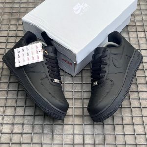 All‑black Nike Air Force 1 sneakers with leather upper, black laces, perforated toe box, and black rubber sole embossed with 'AIR'.